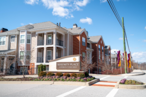 Entrance sign and buildings of Serenity Place apartments under clear blue sky.