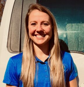 Smiling woman in blue shirt outdoors.