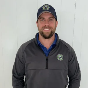 Man smiling, wearing a dark jacket and cap.