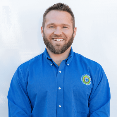 Smiling man in a blue shirt with an embroidered logo.